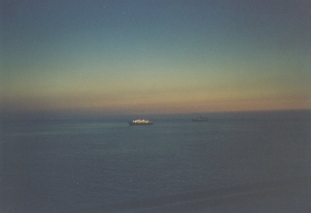 Sunset color on horizon, with ship in the distance fully lighted.